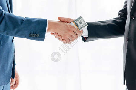 男人向商业伙伴行贿并与白人握手的剪影图片