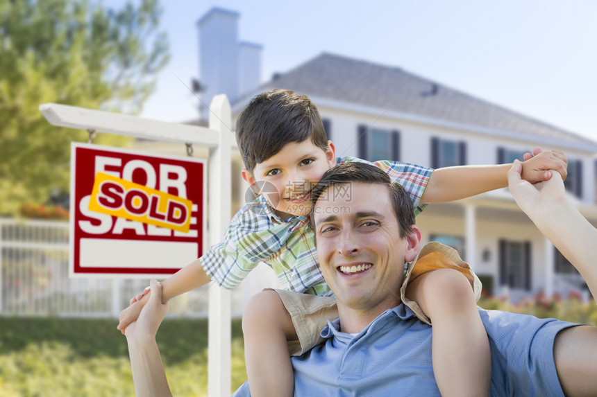 混合种族父子在房子和出售的房地产标志前与一图片