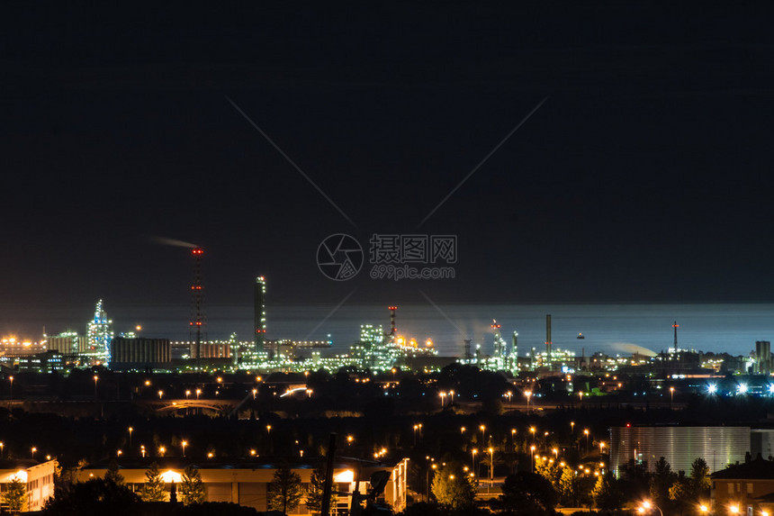 工业建筑石油炼厂和石油化工厂在夜间与后面的海图片