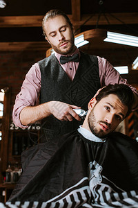 时尚的理发师一边为英俊的男人做发型图片