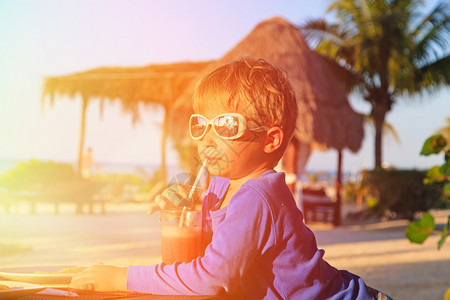 热带海滩上喝西瓜汁的小男孩图片