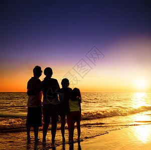 幸福的一家人在沙滩上看日落图片