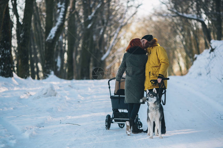 年幼家庭和一只狗在冬季森林中与婴图片
