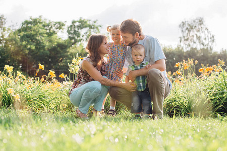 年轻快乐的家庭在户外的花朵里玩得开心情侣抱着可爱的孩子图片