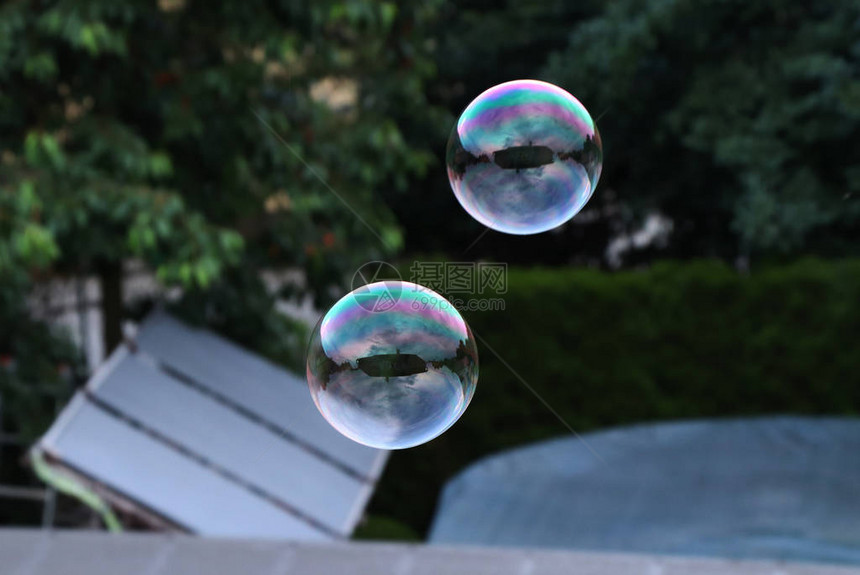 两个气泡在游泳池和花园上方的空中飞舞图片