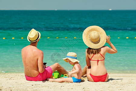 两岁的小孩男在海滩上跟父母玩沙滩玩具和爸图片