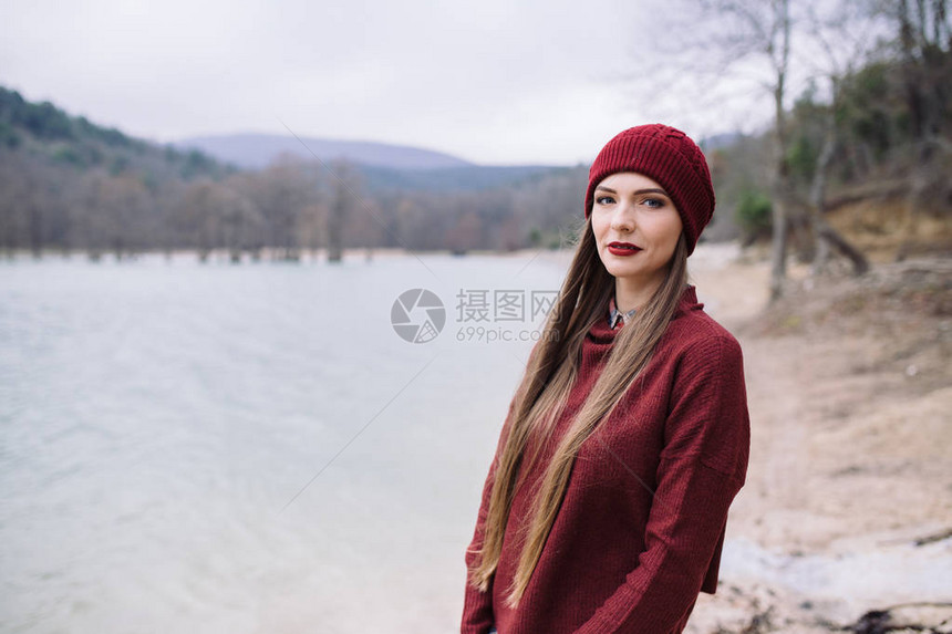 在湖底的布贡迪帽和毛衣中美丽的年轻图片