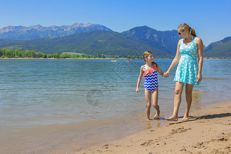 母亲和女儿在风景湖泊背景图片