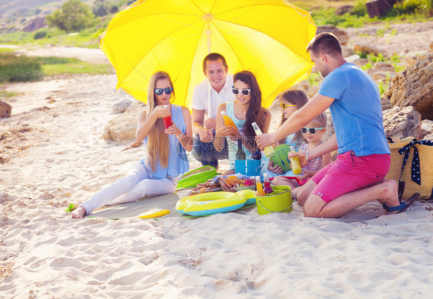 夏日野餐在沙滩上坐在沙地上的朋友们绿色图片