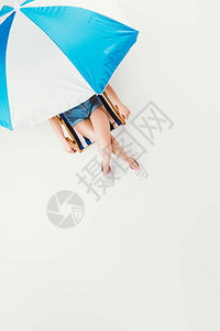 坐在沙滩伞下坐着椅子的女孩的顶部风景图片