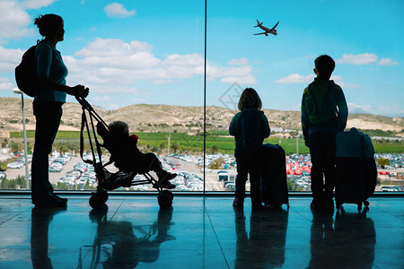 带着孩子和行李的母亲在机场看飞图片