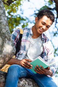 快乐的青少年学生在树下阅读图片