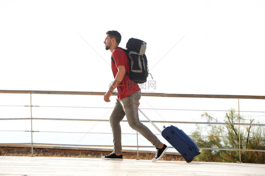 年轻男旅行者带着手提箱和背图片