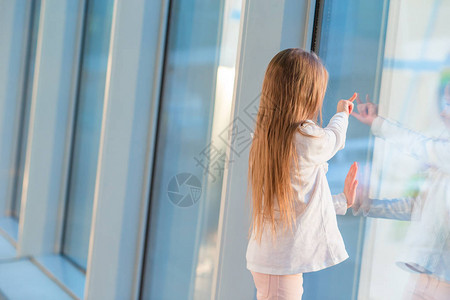 在大窗户附近机场等候登机时长发的小女孩在图片