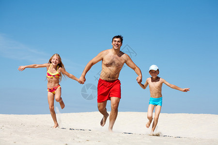 幸福一家人暑假在沙滩上奔跑的照片图片