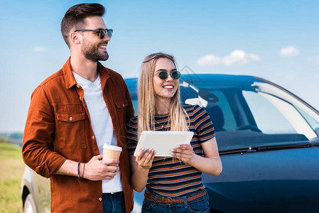 时尚的一对戴太阳眼镜的老夫妇站着咖啡杯和汽车附近的图片