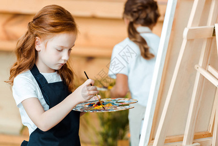 在接近孩子的艺术学校中以可爱的红头发小孩画作图片