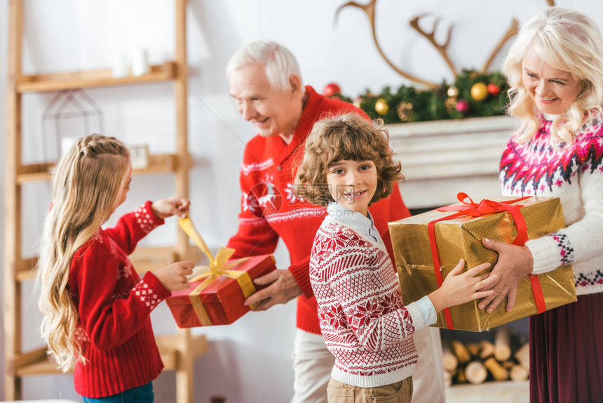 祖父母和快乐的孩子带着礼物盒在圣诞节共图片
