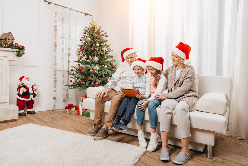 笑着的祖父母和戴着圣塔帽的孩子在圣诞节装饰的房间使用图片