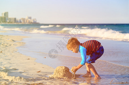 小男孩在夏天沙滩上玩沙图片