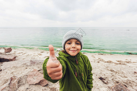 微笑的小男孩在海前竖起大拇指图片