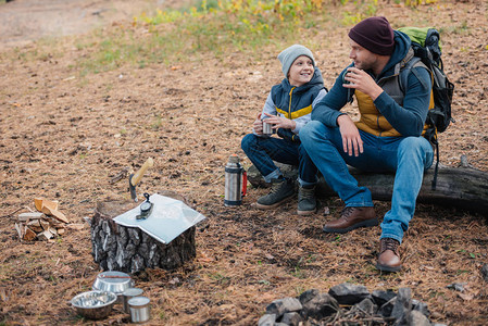 快乐的父亲和儿子在森林温热中喝图片