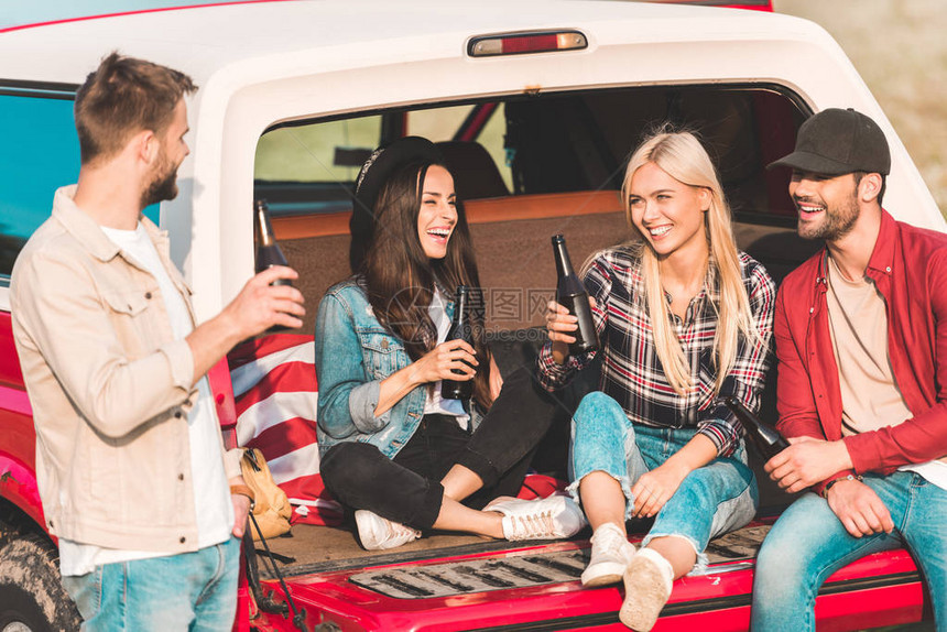 坐在关于自然的汽车后备箱里喝酒聊天和喝啤图片