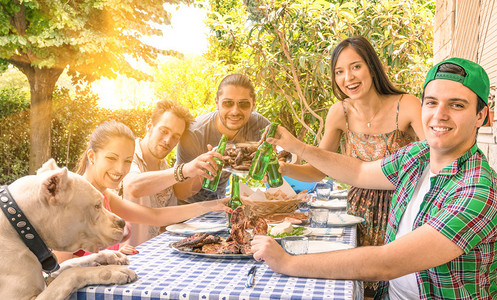一群快乐的朋友在花园烧烤时吃饭和敬酒图片