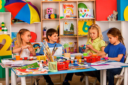 小学生在艺术学校课上画儿童男孩和女孩在桌子上用颜料画幼儿园孩子们的画像孩子们在幼儿园画独立背景图片