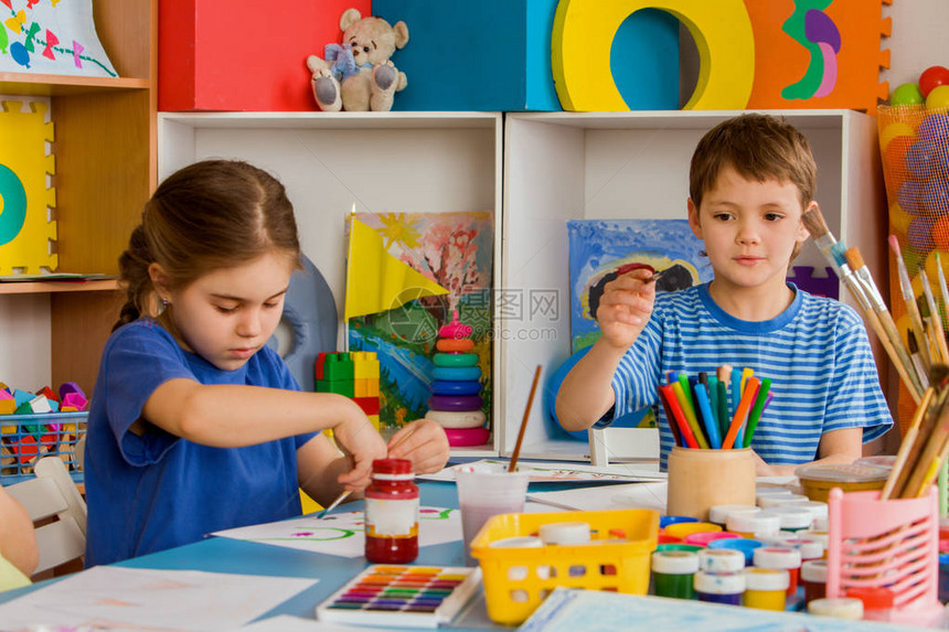 小学生女孩和男孩在艺术学校课上绘画孩子在桌子上用颜料画工艺绘画教育培养孩子的创造能力货架背图片