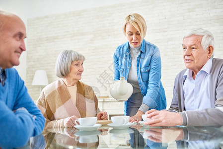 妇女为老年病人倒茶在有帮助的家中生活图片