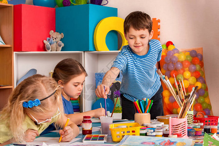 小学生在艺术学校课上画儿童男孩和女孩在桌子上用颜料画幼儿园孩子们的画像水彩画笔背景图片