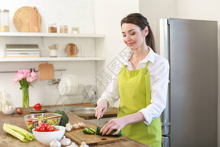 美丽的女人在家里厨房切菜图片