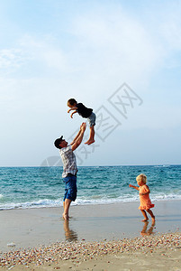 父亲带着两个孩子在海上度假图片