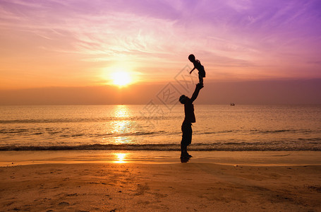 日落海滩上的父子剪影图片