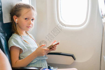 坐在飞机窗边听音乐的小孩儿背景图片