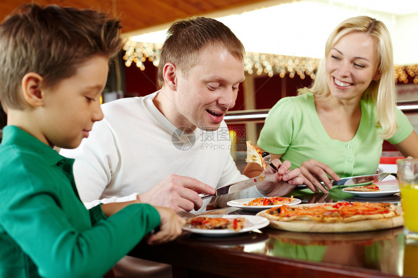 三个家庭吃着美味的比萨图片