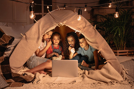 在笔记本电脑上一起坐在帐篷和看电影图片