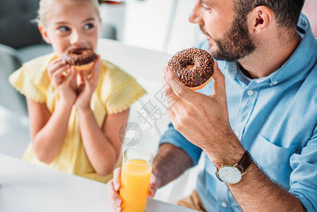 快乐的父亲和女儿在家吃甜圈喝图片