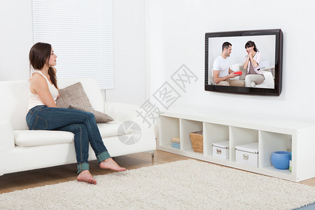 坐在家里沙发上看电视的年青妇女全员图片