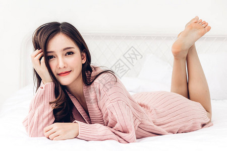 快乐笑容的肖像是女在家里卧室的床上享受和放松Asianbea图片