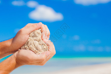 人类握着白色热带海滩的手形成心脏形图片