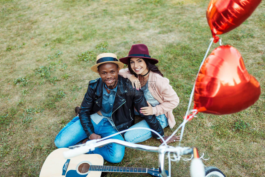跨种族夫妇坐在草地上骑着自行车图片