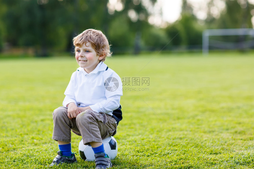 有趣的4岁小男孩在户外足球场上踢足球后休息带小孩的积极休图片