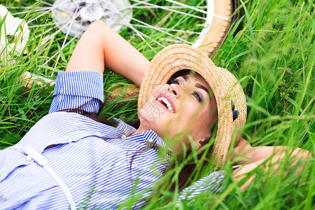 快乐的女人躺在绿草地上微笑图片