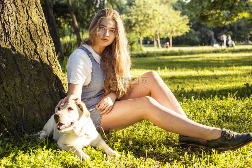 年轻有吸引力的金发美女在夏日绿公园玩她的狗生活方式的人概念图片
