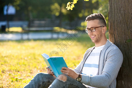 英俊的男人在公园看书图片