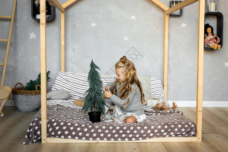 小女孩坐在床上装饰小圣诞树圣诞快背景图片