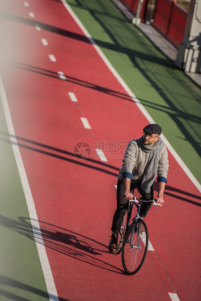 英俊成年男子在新油漆的自行车路上骑自行车的图片
