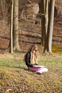 坐在草地上看书的金发女图片